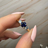 "Bluzz" Round Cut 1.5 Carat Blue Sapphire Trilogy Yellow Gold Engagement Ring Life style- Front view